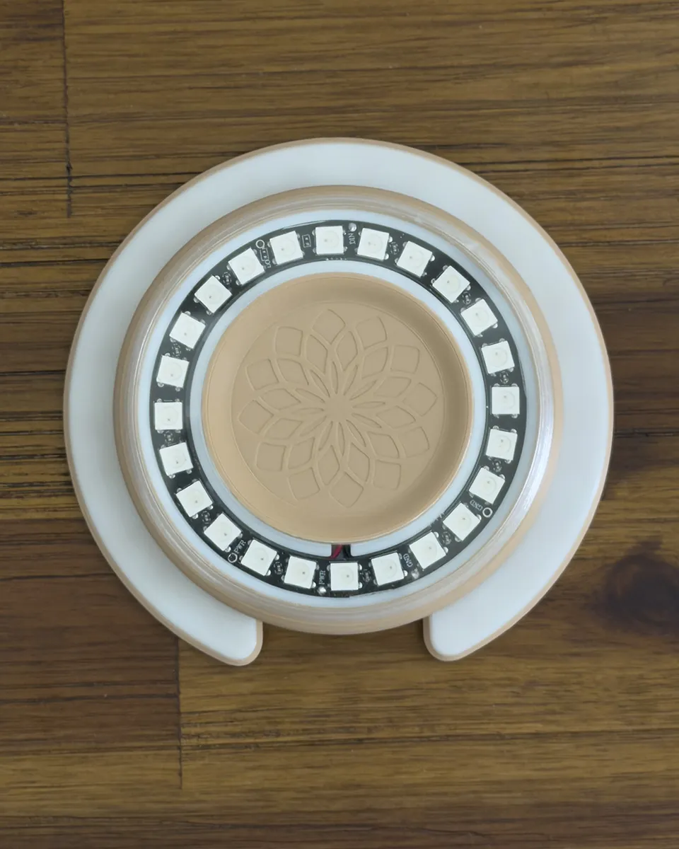 Top-down view of the Aura Light with the clear cover on, its ring of LEDs reading as crisp, defined points around the flower-engraved center