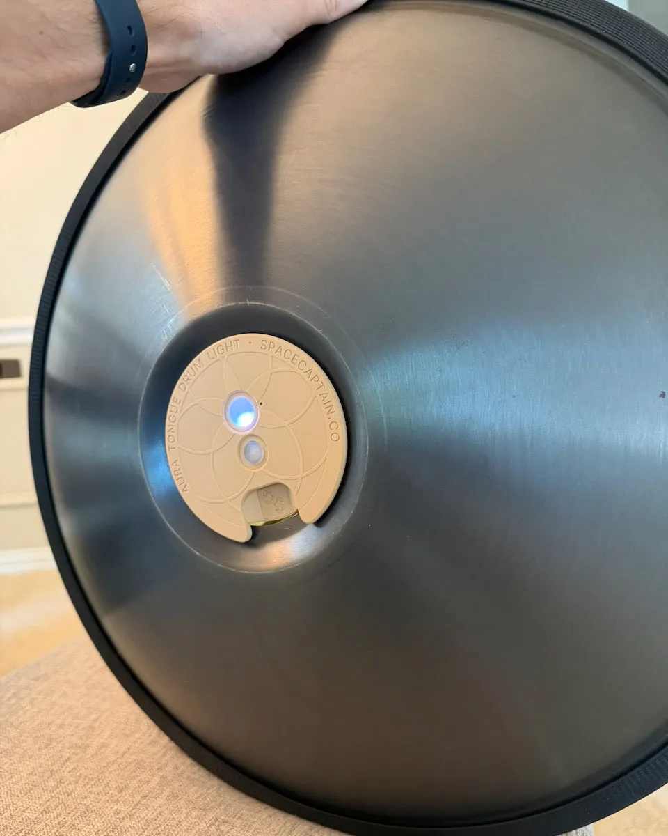 Underside of the RAV Vast held up to show the Aura Light magnetically attached at the center, engraved "Aura Tongue Drum Light · spacecaptain.co"